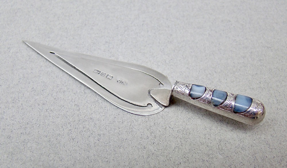 A Victorian sterling silver trowel-shaped bookmark with an agate handle inside a red leather Harrods case. View II