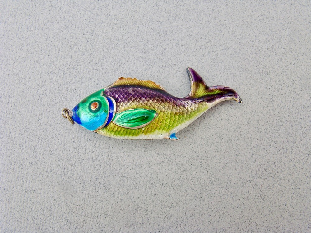 A silver fish-shaped pendant featuring green and purple guilloche enamel across the body and a suspension loop at the mouth. View II