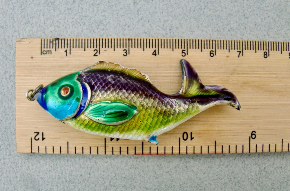 A silver fish-shaped pendant featuring green and purple guilloche enamel across the body and a suspension loop at the mouth. View IV