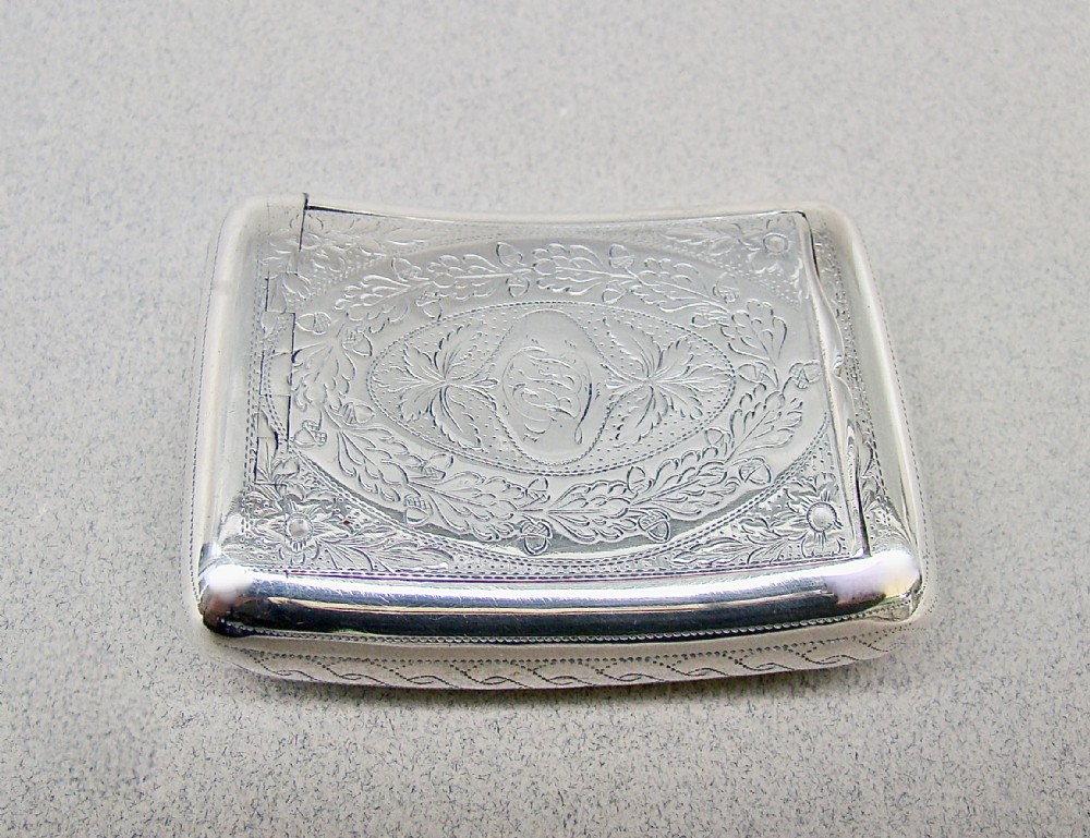 A rectangular Georgian sterling silver snuff box featuring hand-engraved oak leaf motifs, a central monogram cartouche, and a curved profile.