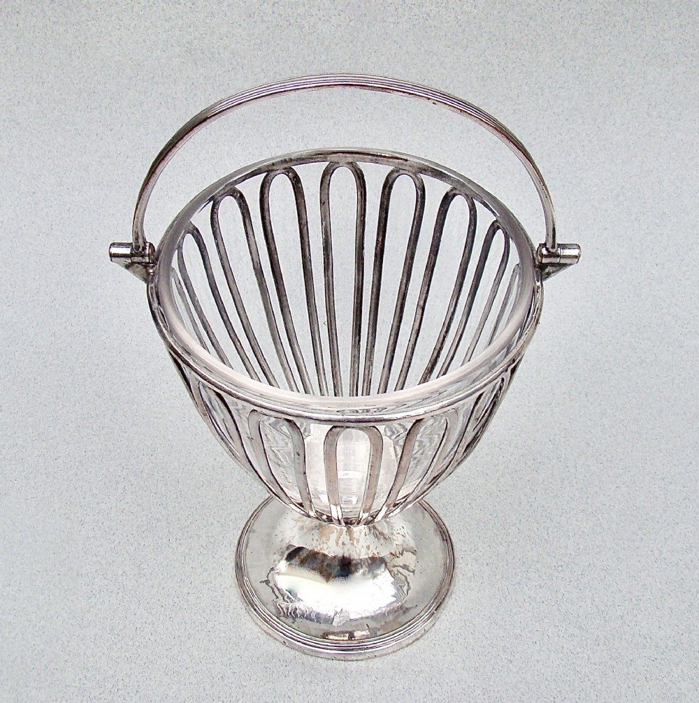 A Georgian Old Sheffield Plate wirework sugar vase featuring an arched swing handle, loop-pattern wire body, and a turned pedestal base.
