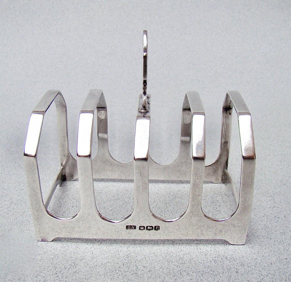 An Art Deco solid silver four-slice toast rack featuring angular dividers and a geometric central handle. View II