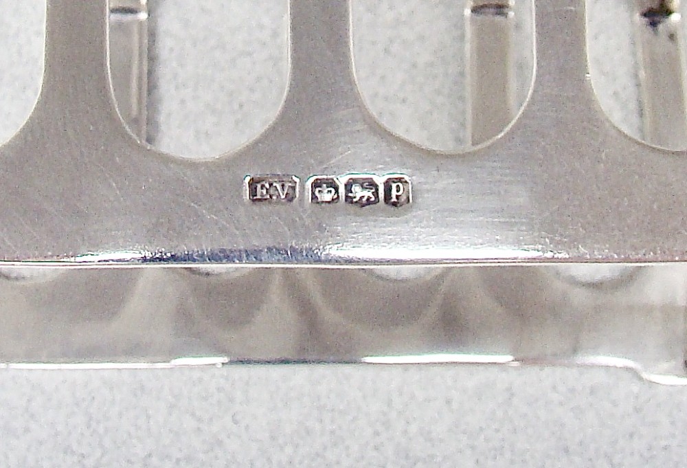 An Art Deco solid silver four-slice toast rack featuring angular dividers and a geometric central handle. View IV