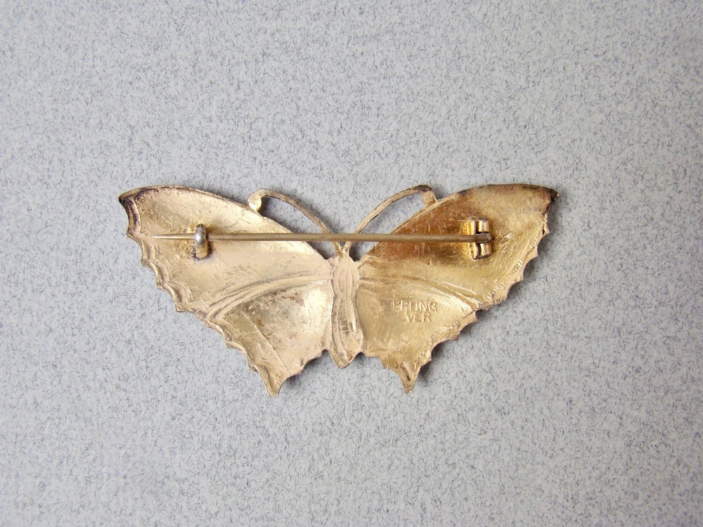 A butterfly brooch constructed from sterling silver featuring bright green, turquoise, and blue guilloche enamel across the wings and body. View IV