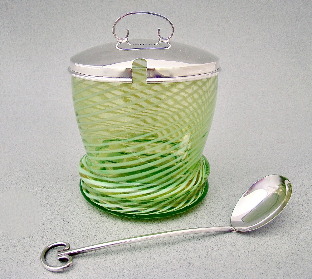 A green spiral-patterned vaseline glass preserve pot with a polished hallmarked silver lid and matching silver spoon. View II