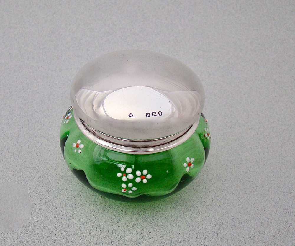 A small green glass jar decorated with white enamel flowers and topped with a hallmarked sterling silver cap. View II