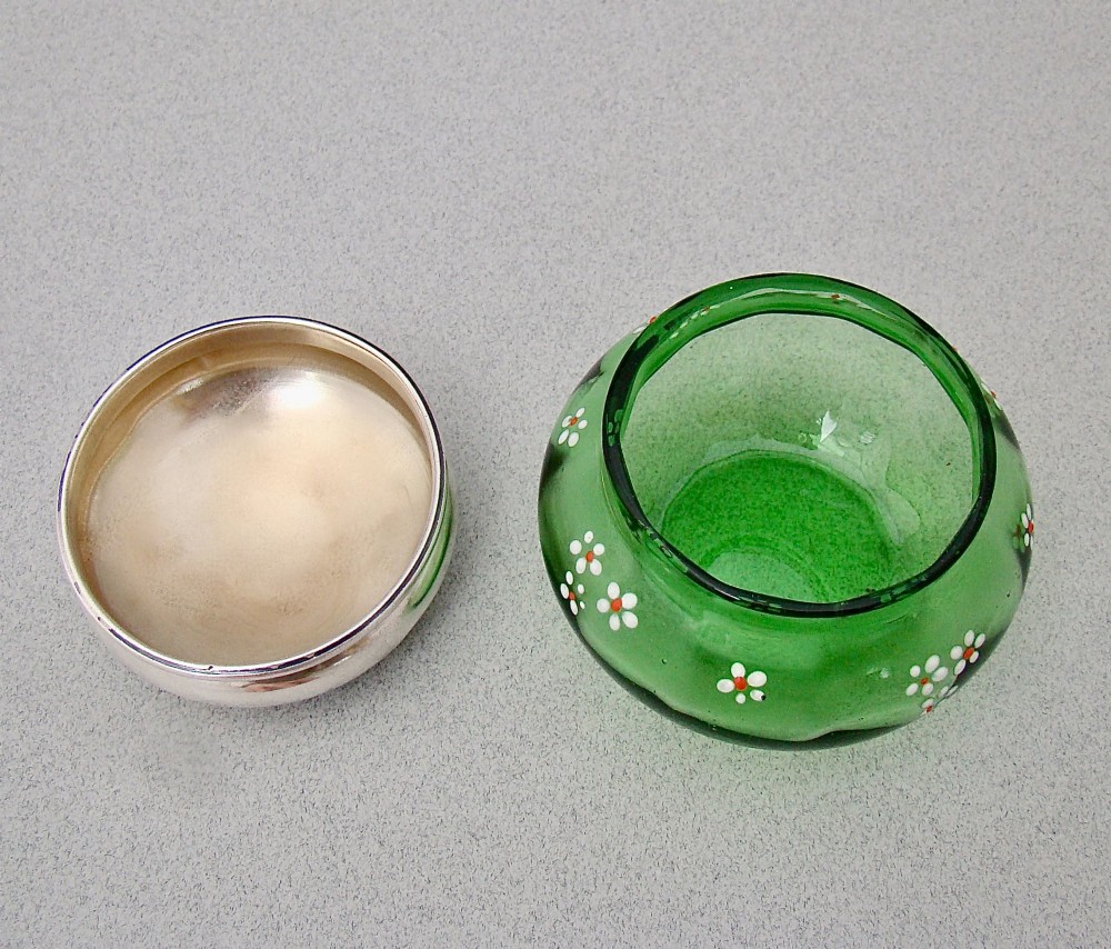 A small green glass jar decorated with white enamel flowers and topped with a hallmarked sterling silver cap. View V