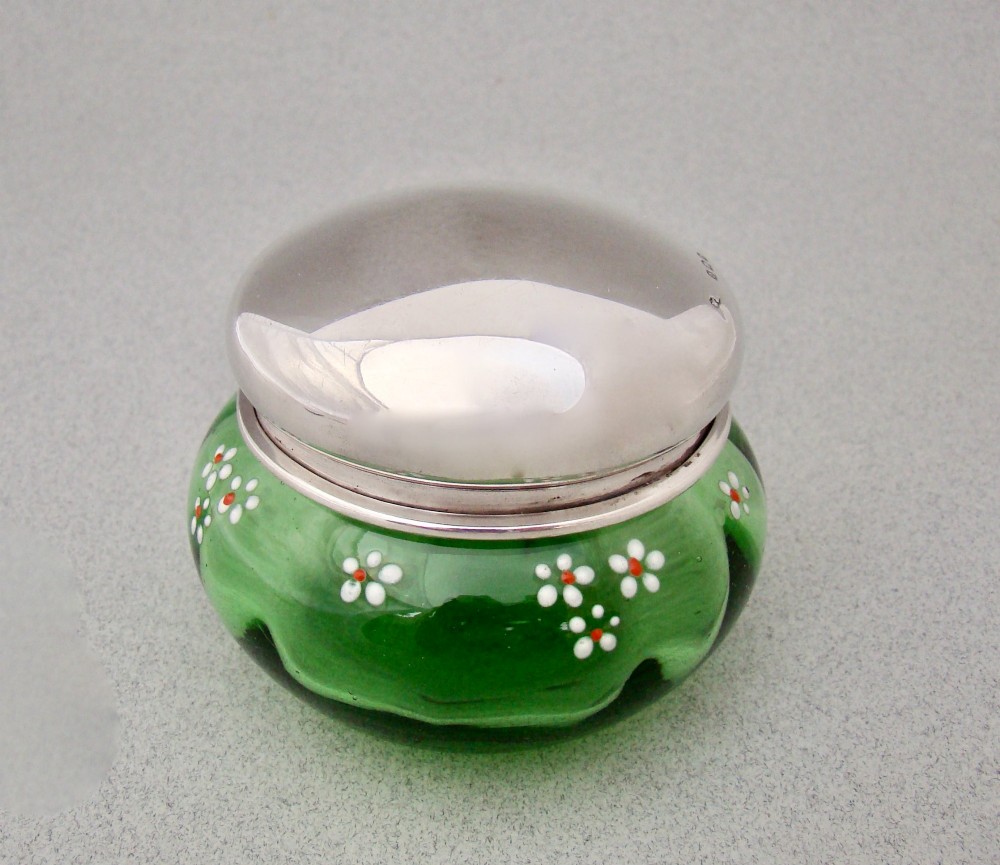 A small green glass jar decorated with white enamel flowers and topped with a hallmarked sterling silver cap. View VI