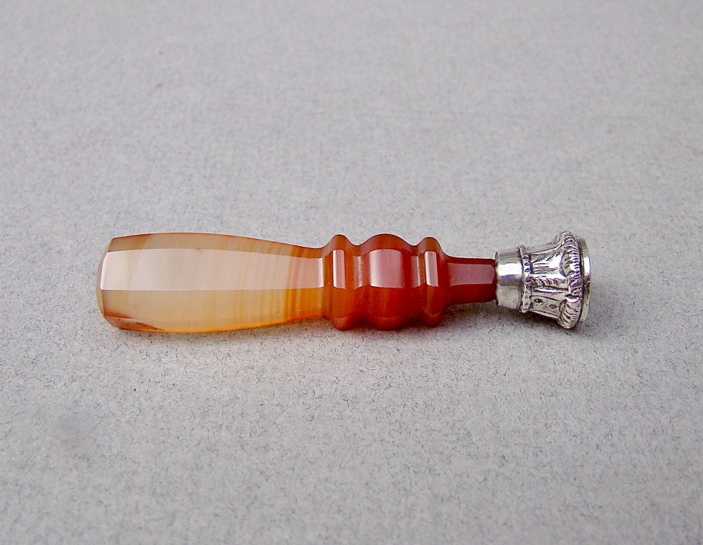 A Victorian desk seal featuring a carved red and cream banded agate handle with an engraved silver mount. View II