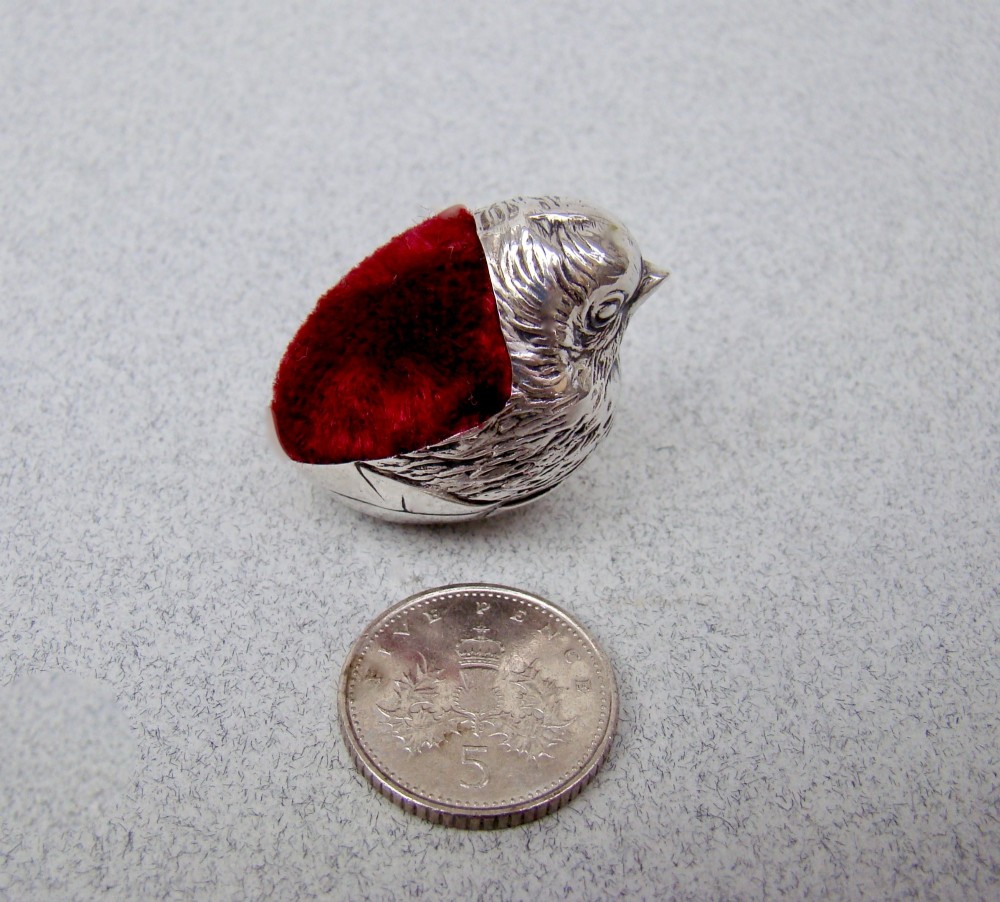 An Edwardian sterling silver pin cushion formed as a hatching chick emerging from an eggshell with a red velvet insert. View III