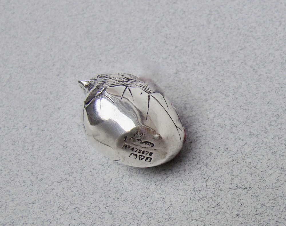 An Edwardian sterling silver pin cushion formed as a hatching chick emerging from an eggshell with a red velvet insert. View IV