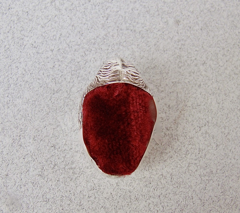 An Edwardian sterling silver pin cushion formed as a hatching chick emerging from an eggshell with a red velvet insert. View VI