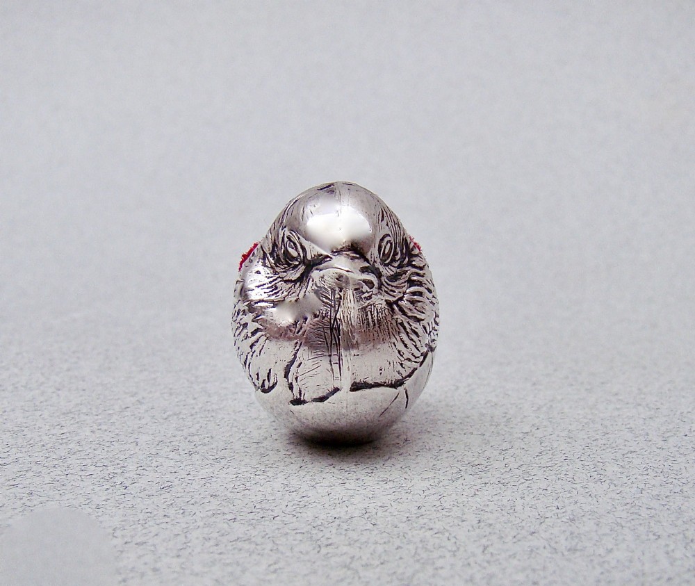 An Edwardian sterling silver pin cushion formed as a hatching chick emerging from an eggshell with a red velvet insert. View VII