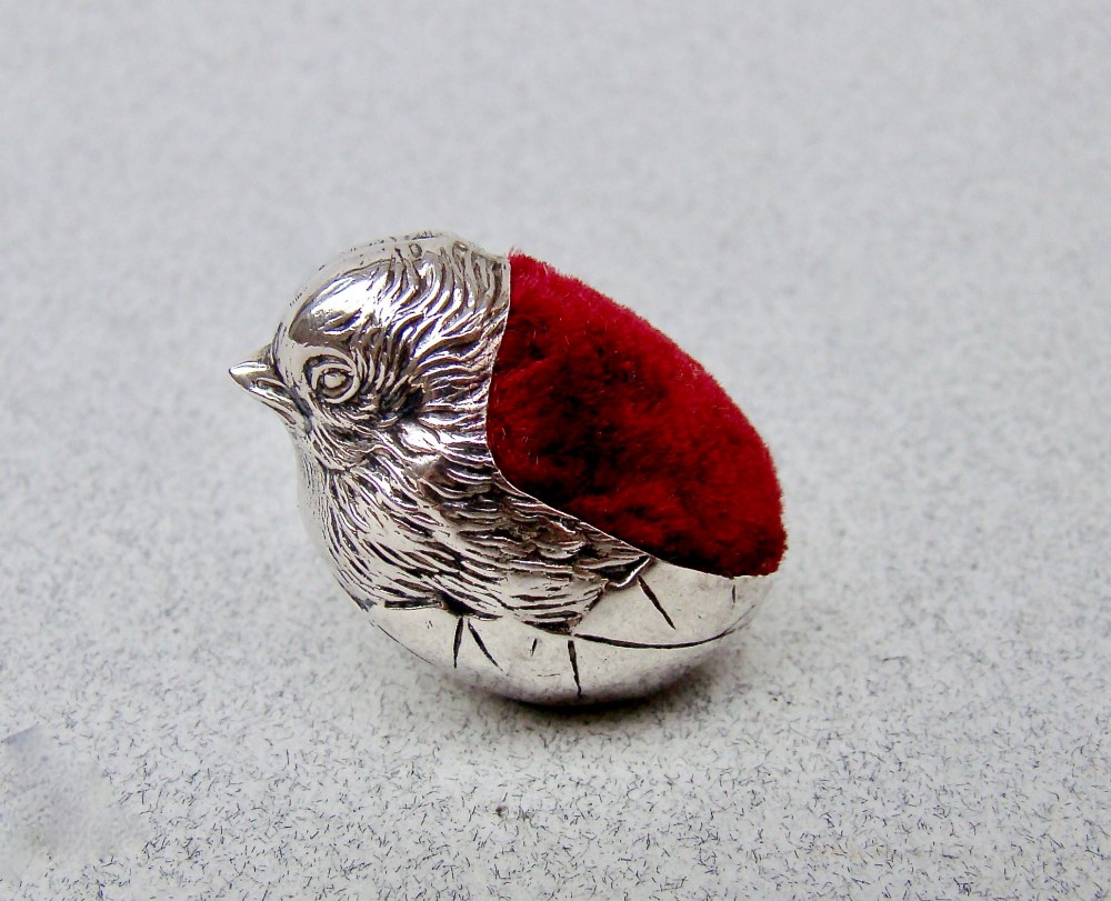 An Edwardian sterling silver pin cushion formed as a hatching chick emerging from an eggshell with a red velvet insert. View VIII