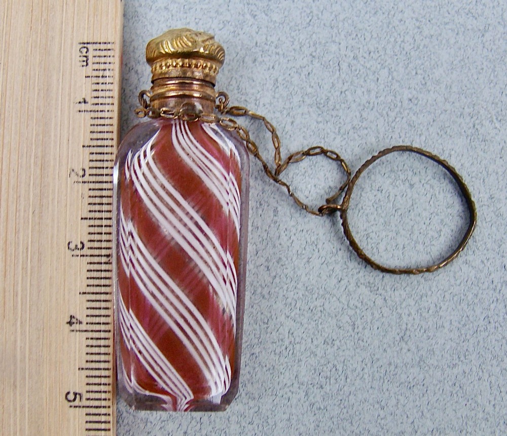 A miniature 19th-century French Clichy clear glass scent bottle featuring internal pink and white diagonal swirls, topped with an embossed gilt brass cap and suspension ring. View III