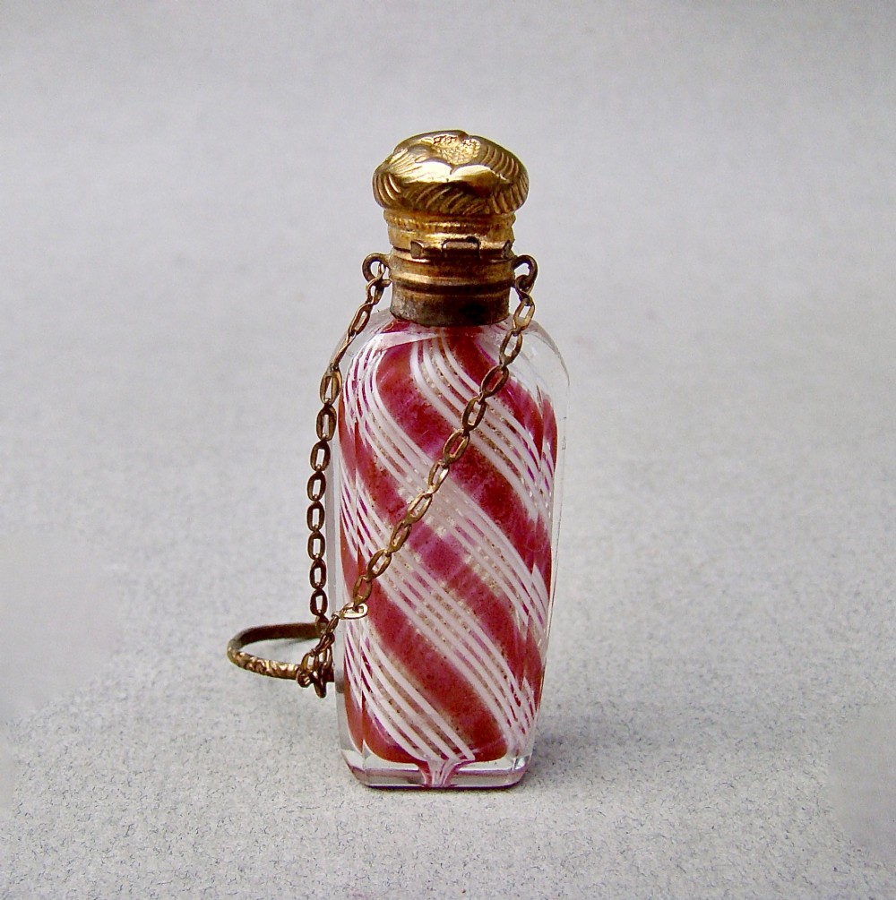 A miniature 19th-century French Clichy clear glass scent bottle featuring internal pink and white diagonal swirls, topped with an embossed gilt brass cap and suspension ring. View IV