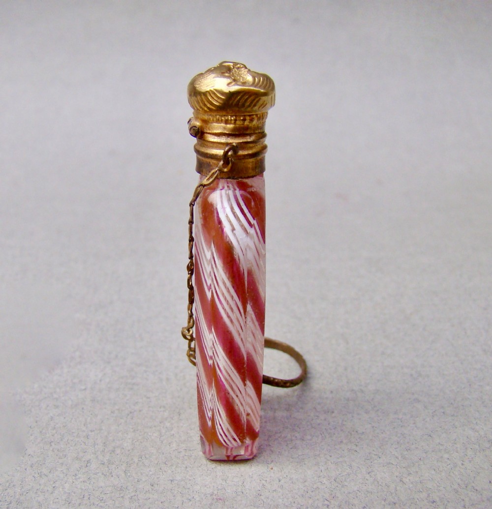 A miniature 19th-century French Clichy clear glass scent bottle featuring internal pink and white diagonal swirls, topped with an embossed gilt brass cap and suspension ring. View VI