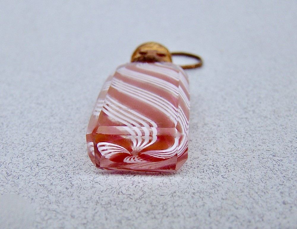 A miniature 19th-century French Clichy clear glass scent bottle featuring internal pink and white diagonal swirls, topped with an embossed gilt brass cap and suspension ring. View VII