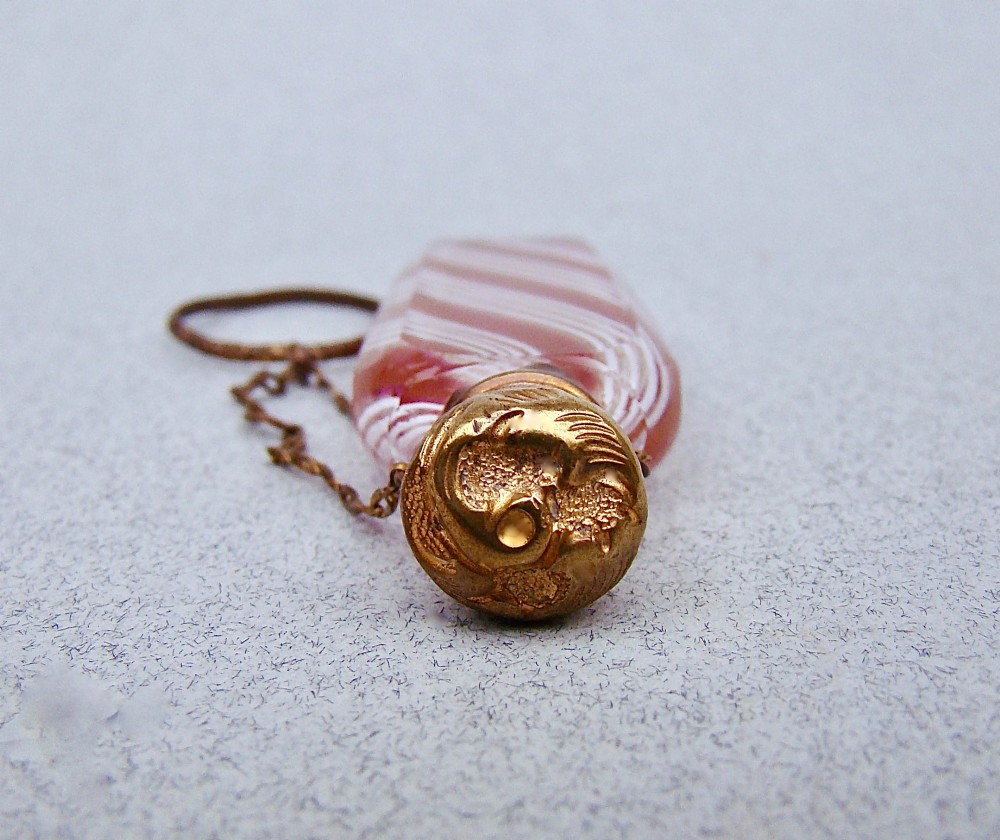 A miniature 19th-century French Clichy clear glass scent bottle featuring internal pink and white diagonal swirls, topped with an embossed gilt brass cap and suspension ring. View VIII