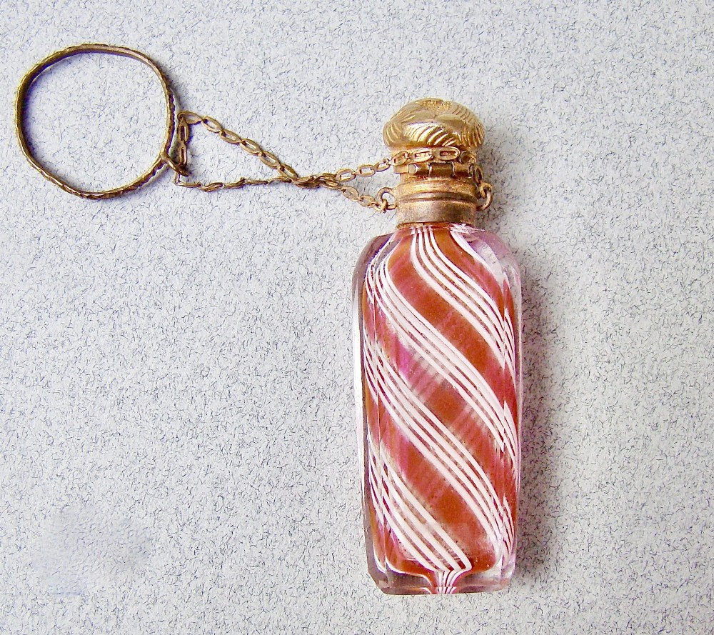 A miniature 19th-century French Clichy clear glass scent bottle featuring internal pink and white diagonal swirls, topped with an embossed gilt brass cap and suspension ring. View IX