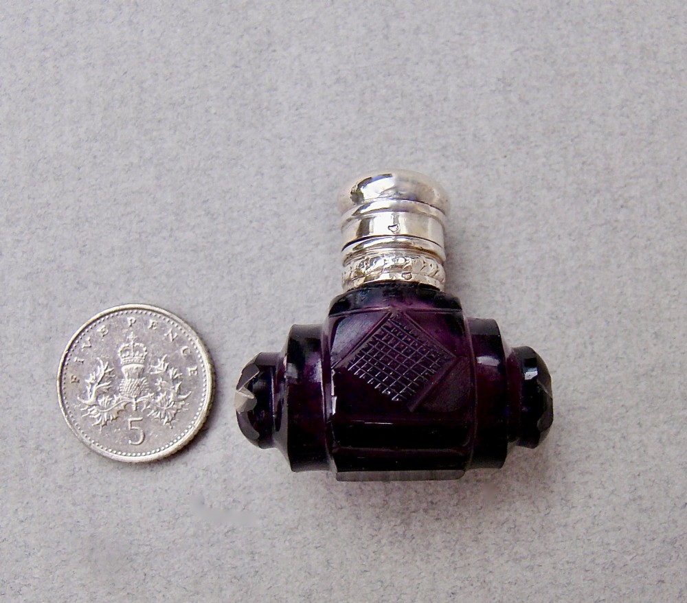 A miniature barrel-shaped purple amethyst cut glass scent bottle with a silver cap and collar. View II