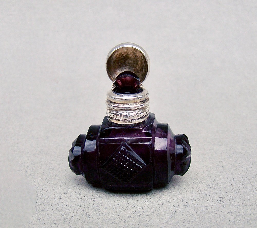 A miniature barrel-shaped purple amethyst cut glass scent bottle with a silver cap and collar. View III