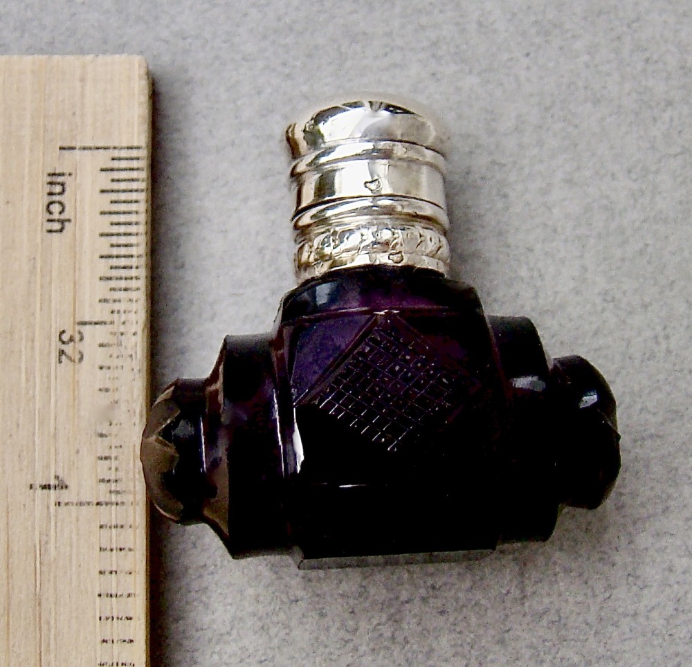 A miniature barrel-shaped purple amethyst cut glass scent bottle with a silver cap and collar. View IV