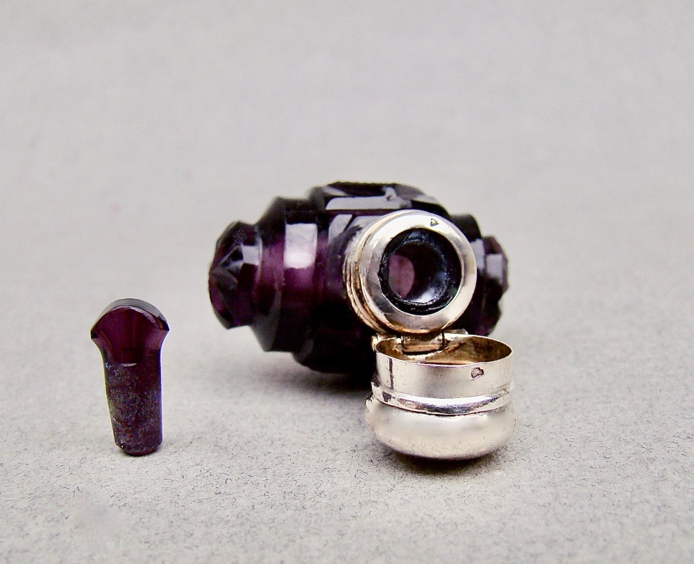 A miniature barrel-shaped purple amethyst cut glass scent bottle with a silver cap and collar. View V