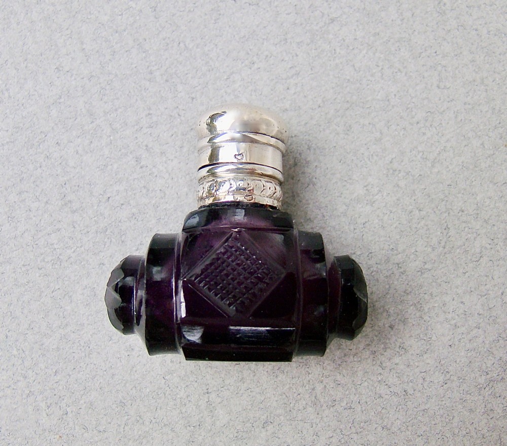 A miniature barrel-shaped purple amethyst cut glass scent bottle with a silver cap and collar. View VIII