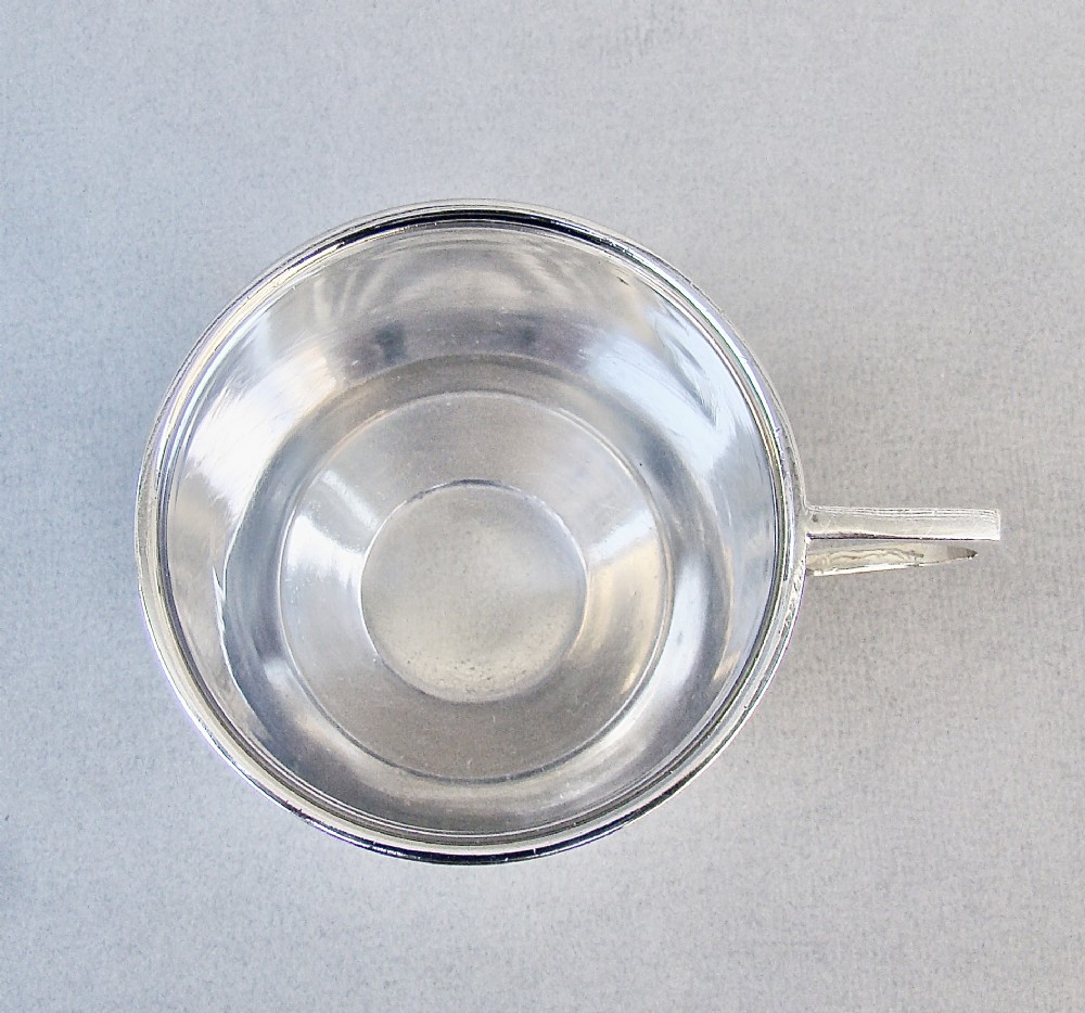 A sterling silver Art Deco christening mug with a flared body, geometric angular handle, and stepped pedestal base. View III