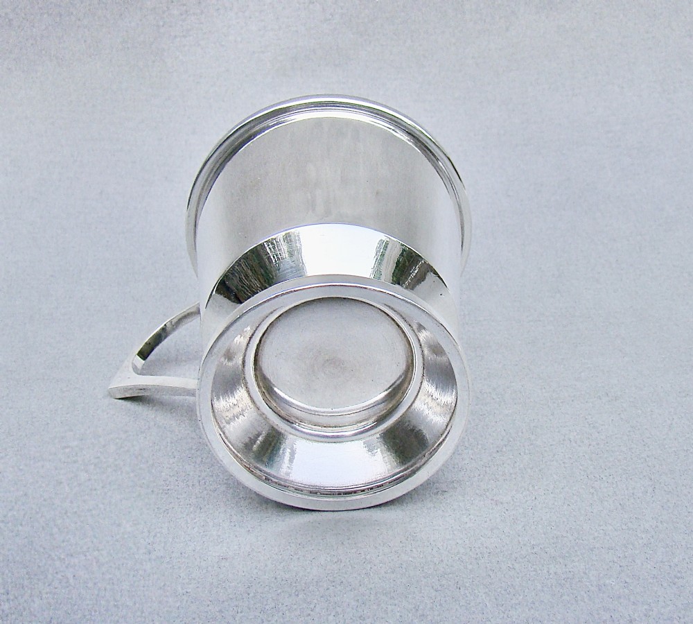 A sterling silver Art Deco christening mug with a flared body, geometric angular handle, and stepped pedestal base. View V