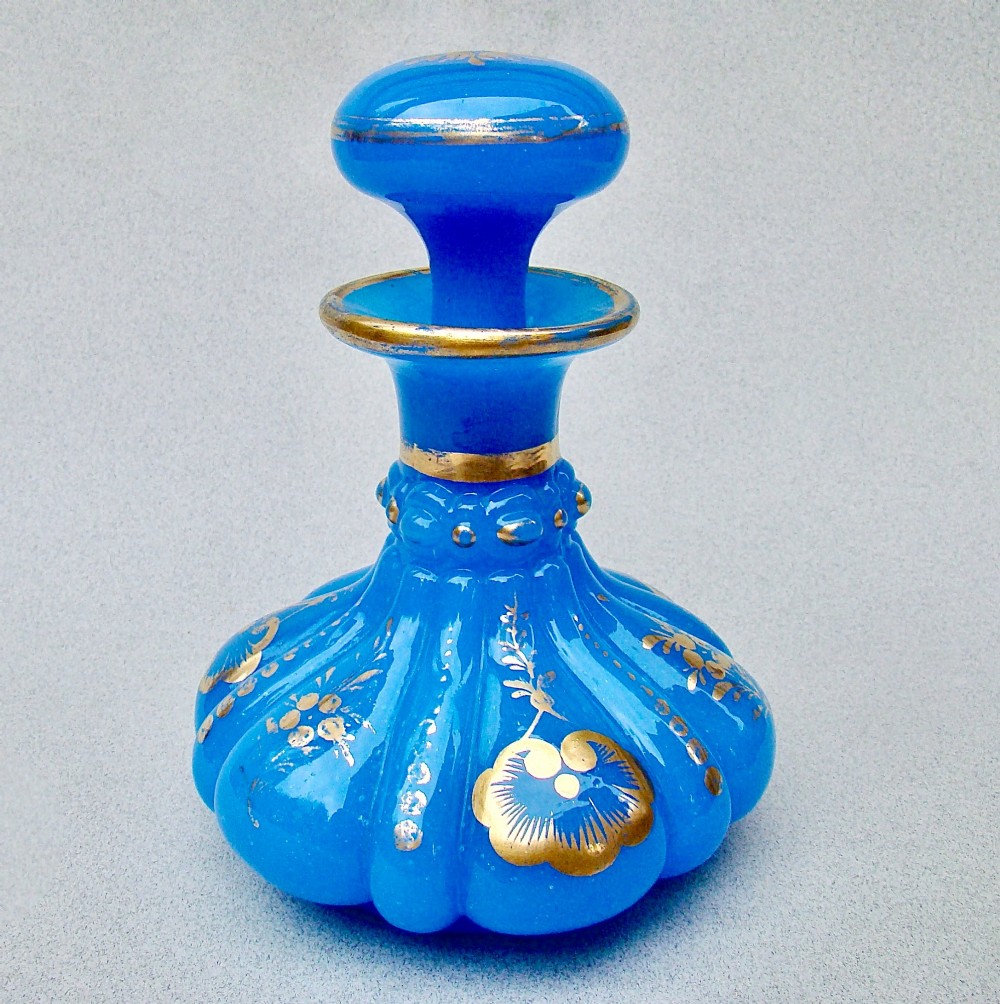 A bright blue lobed opaline glass scent bottle with a flared rim, ground glass stopper, and hand-gilded floral motifs. View VIII