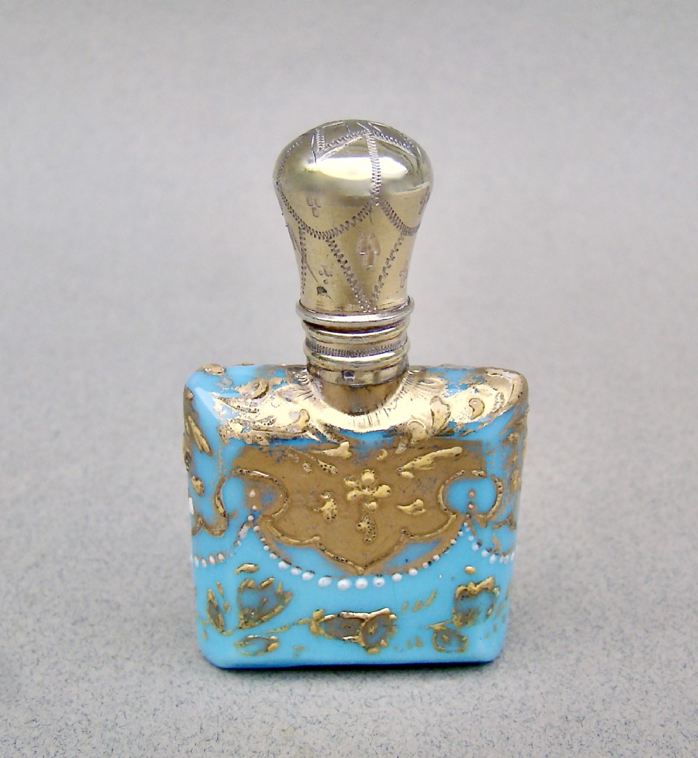 A small rectangular turquoise glass scent bottle featuring intricate gold scrollwork, white beaded enamel, and an engraved silver-gilt cap. View II