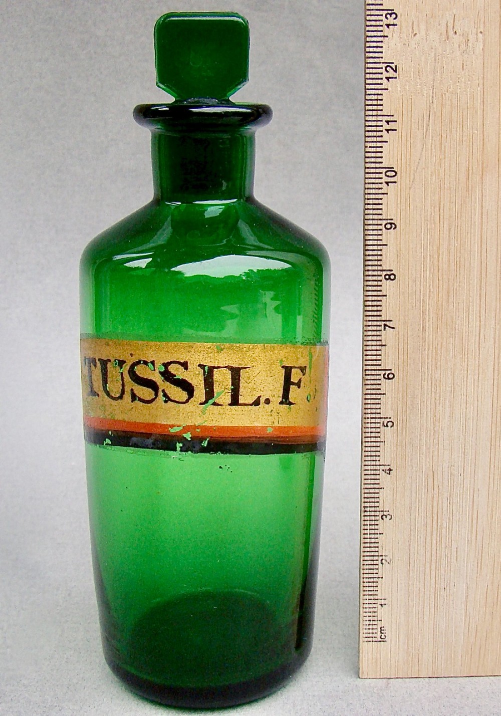 A pair of late Victorian cylindrical Bristol green glass apothecary bottles with ground stoppers and gilt-painted labels. View III