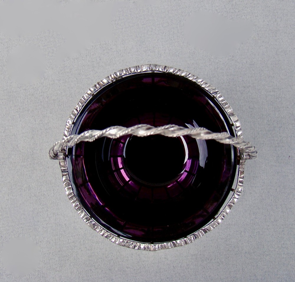 A sterling silver wirework sugar basket featuring a twisted swing handle, cast vine leaf motifs, and a removable purple glass liner. View III