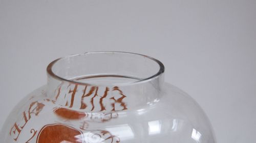 fig 4. A clear glass spirit dispenser featuring gilt typography reading Fine Pale Brandy, a spire finial lid, and a brass spigot at the base.