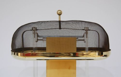 fig 3. A hand-cranked Van de Graaff electrostatic generator featuring a black metal base, transparent acrylic supports, an upright rubber belt, and a wire mesh upper dome trimmed in brass.