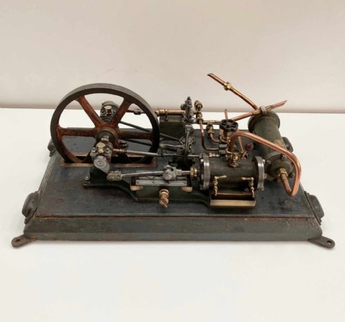 fig 1. Late nineteenth-century stationary steam engine scale model with a large flywheel, brass valves, and copper piping mounted on a painted rectangular plinth.