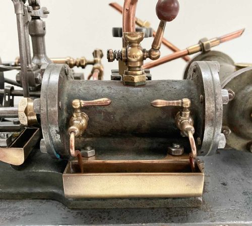 fig 2. Late nineteenth-century stationary steam engine scale model with a large flywheel, brass valves, and copper piping mounted on a painted rectangular plinth.
