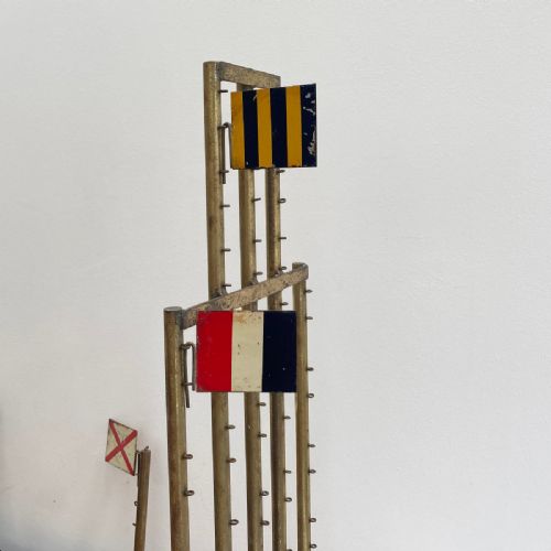 fig 4. An open early twentieth-century black wooden box featuring internal compartments with miniature signal flags and upright brass masts displaying colourful painted flags.