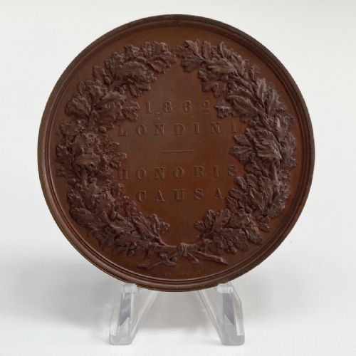 fig 3. A circular dark brown bronze medallion featuring high-relief classical allegorical figures surrounding a seated Britannia with a recumbent lion at her feet.