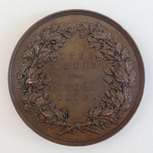 fig 1. A circular Victorian bronze prize medal featuring classical figures representing arts and industry surrounding Britannia above a reclining lion.