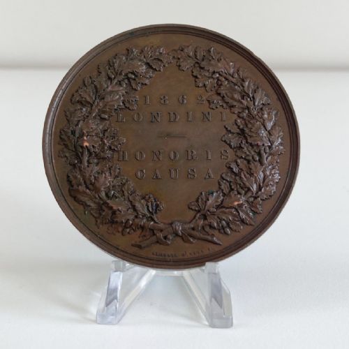 fig 2. A circular Victorian bronze prize medal featuring classical figures representing arts and industry surrounding Britannia above a reclining lion.