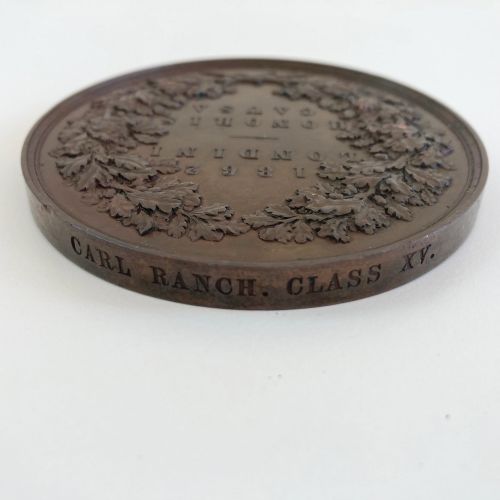 fig 4. A circular Victorian bronze prize medal featuring classical figures representing arts and industry surrounding Britannia above a reclining lion.