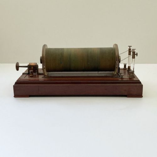 fig 1. An antique 19th-century Ruhmkorff induction coil featuring a central cloth-wrapped wire cylinder, brass fittings, glass discharge tubes, and a polished mahogany base.