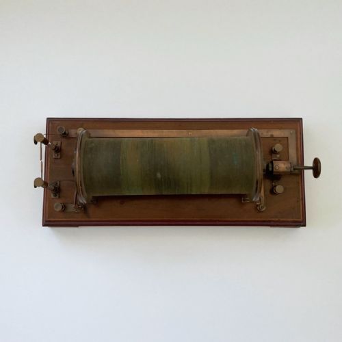 fig 2. An antique 19th-century Ruhmkorff induction coil featuring a central cloth-wrapped wire cylinder, brass fittings, glass discharge tubes, and a polished mahogany base.