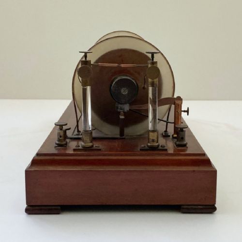 fig 4. An antique 19th-century Ruhmkorff induction coil featuring a central cloth-wrapped wire cylinder, brass fittings, glass discharge tubes, and a polished mahogany base.