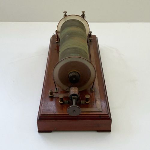 fig 5. An antique 19th-century Ruhmkorff induction coil featuring a central cloth-wrapped wire cylinder, brass fittings, glass discharge tubes, and a polished mahogany base.