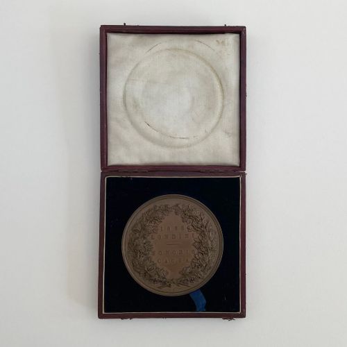 fig 1. An antique 1862 London International Exhibition bronze medal resting inside its original opened maroon presentation case with blue velvet lining.