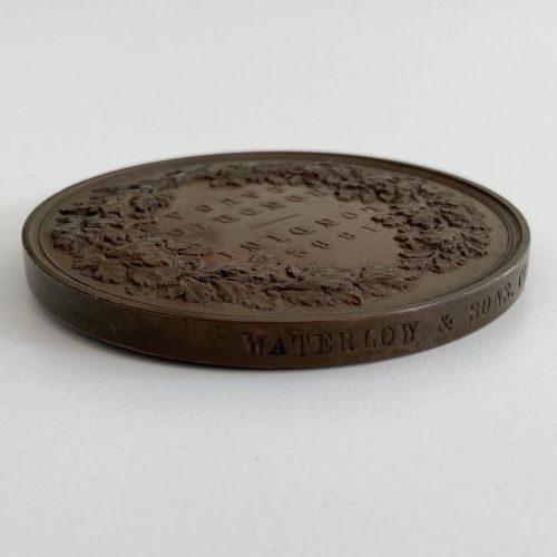 fig 7. An antique 1862 London International Exhibition bronze medal resting inside its original opened maroon presentation case with blue velvet lining.